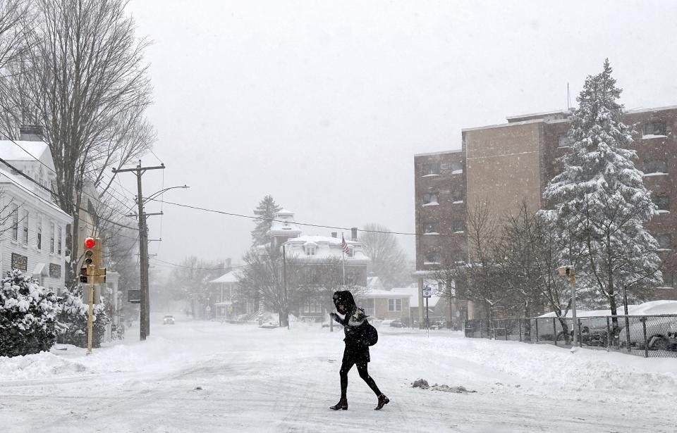 A person walks across a street as snow falls in Portsmouth, N.H., Sunday, Jan. 7, 2024. A major winter storm bringing up to a foot of snow and freezing rain to some communities spread across New England Sunday sending residents scurrying to pull out their shovels and snow blowers to clear sidewalks and driveways. Winter storm warnings and watches were in effect throughout the Northeast, and icy roads made for hazardous travel as far south as North Carolina. (AP Photo/Caleb Jones)