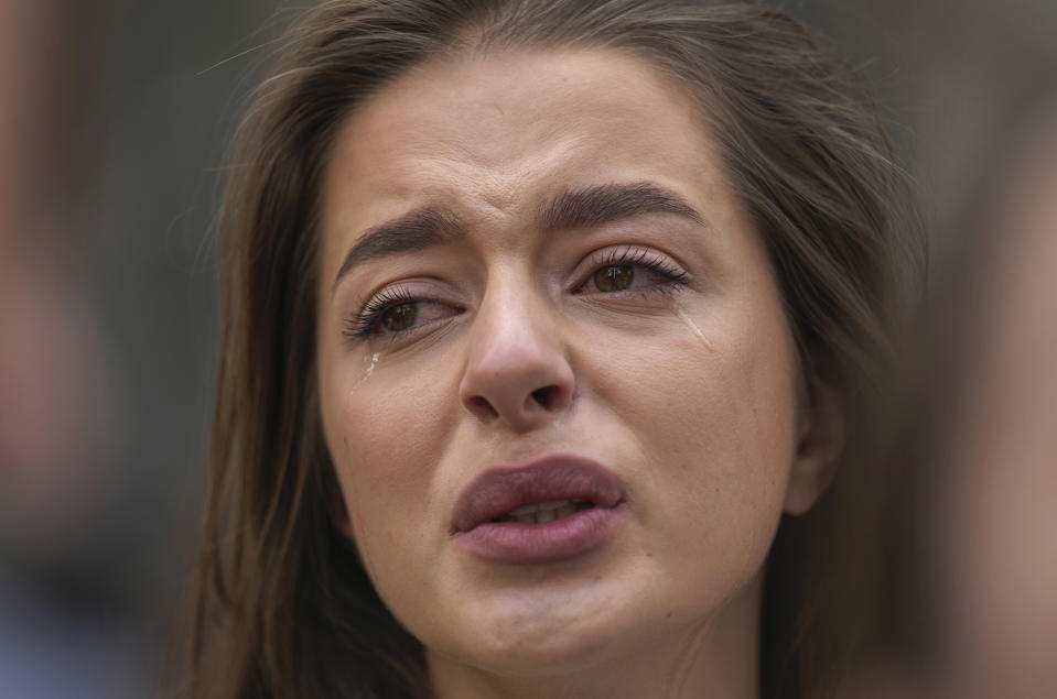 One of Ukrainian people living in Thailand cries as they listen to national anthem during a rally to mark the one-year anniversary of Russia's invasion of Ukraine, in Bangkok, Thailand, Friday, Feb. 24, 2023. (AP Photo/Sakchai Lalit)