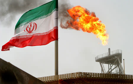 FILE PHOTO: A gas flare on an oil production platform in the Soroush oil fields is seen alongside an Iranian flag in the Persian Gulf, Iran, July 25, 2005. REUTERS/Raheb Homavandi/File Photo/File Photo