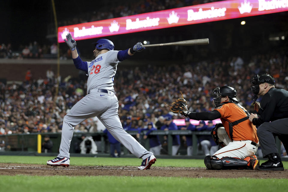 Los Angeles Dodgers' J.D. Martinez follows through on a three-run home run in front of San Francisco Giants catcher Blake Sabol during the sixth inning of a baseball game in San Francisco, Friday, Sept. 29, 2023. (AP Photo/Jed Jacobsohn)