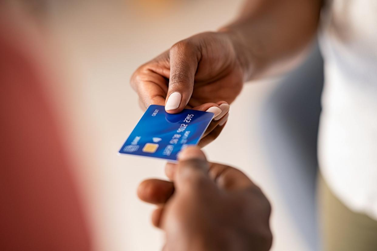 Close up hands of a black woman giving bank credit card to man. Detail shot of a woman passing a payment credit card to the seller. Hand of african american man receiving payment from customer.