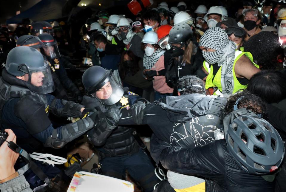 Police clash with pro-Palestinian protesters at UCLA at night.