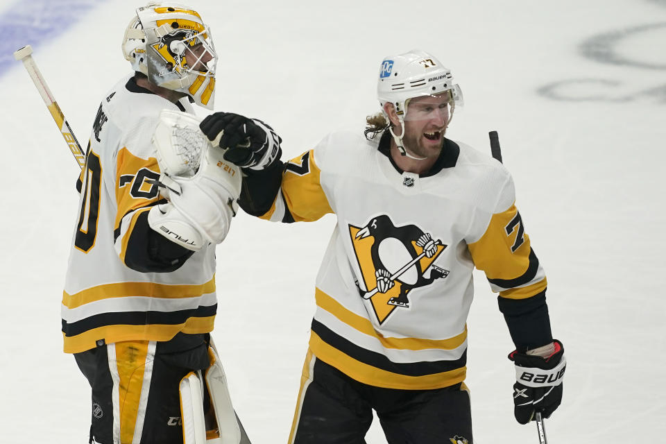Pittsburgh Penguins goaltender Louis Domingue, left, celebrates with center Jeff Carter (77) after the Penguins defeated the San Jose Sharks in an NHL hockey game in San Jose, Calif., Saturday, Jan. 15, 2022. The Penguins won, 2-1, in overtime. (AP Photo/Jeff Chiu)