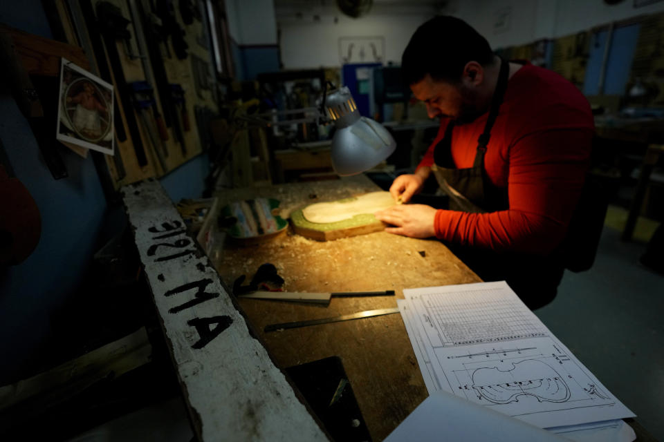 Milan's Opera maximum security prison inmate Nikolae (last name not available) works on the top plate of a violin made from the wood of wrecked migrants' boat in the prison's lab, near Milan, northern Italy, Friday, Feb. 9, 2024. Inmates at Opera used the wood of wrecked boats sailed by migrants across the Sicily Channel to craft the musical instruments that the 'Sea Orchestra' used during their debut at La Scala Opera House in Milan on Monday, Feb. 12, 2024. The violins, violas and cellos played by the Orchestra of the Sea in its debut performance Monday at Milan's famed Teatro all Scala carry with them tales of hardship. (AP Photo/Antonio Calanni)