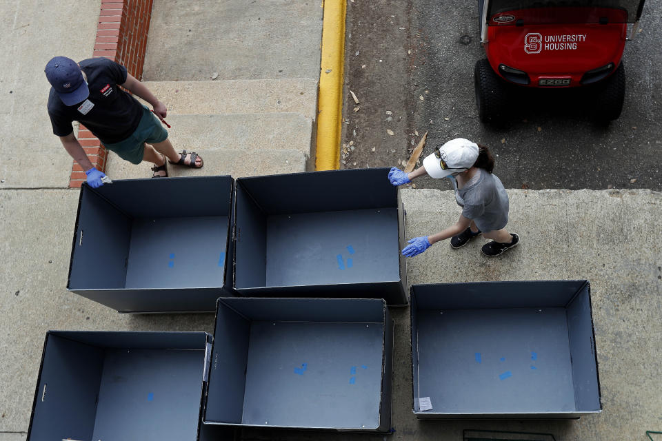 Volunteers clean carts as college students begin moving in for the fall semester at N.C. State University in Raleigh, N.C., Friday, July 31, 2020. The first wave of college students returning to their dorms aren’t finding the typical mobs of students and parents. At N.C. State, the return of students was staggered over 10 days and students were greeted Friday by socially distant volunteers donning masks and face shields. (AP Photo/Gerry Broome)