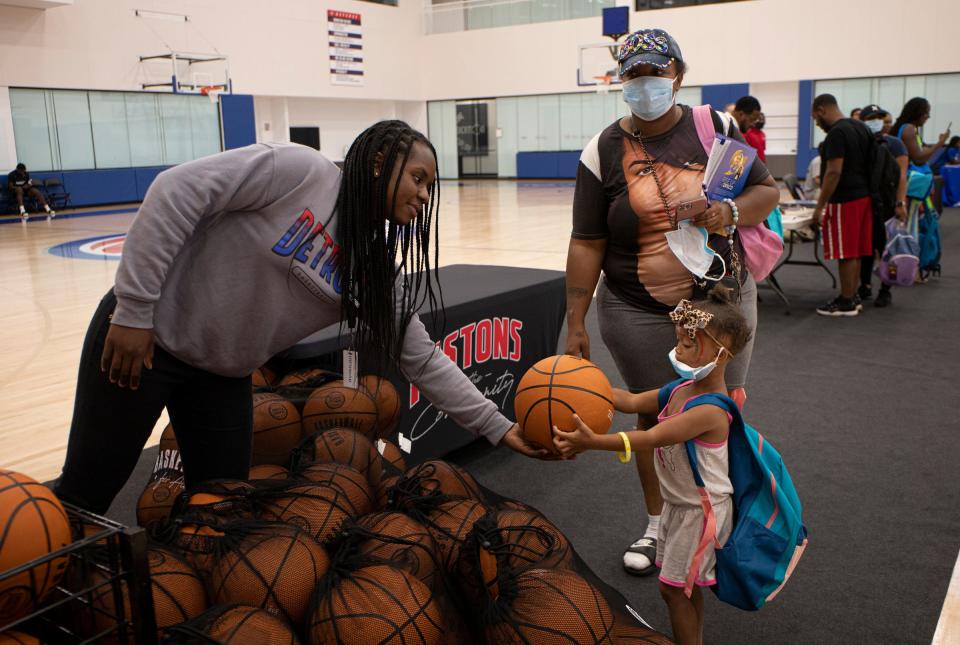 Lyric Hightower, 2, of Detroit, receives a basketball from Pistons intern Lauren Palmer, 22, of Detroit, during the Pistons' back to school drive at the Detroit Pistons Performance center in New Center, Detroit, on Monday, Aug. 15, 2022.