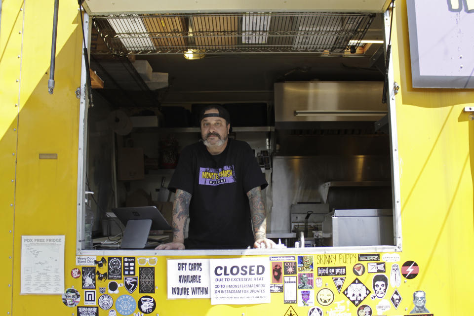 Rico Loverde, chef and owner of the food cart Monster Smash Burgers, stands inside his broiling food cart in Portland, Ore., on Wednesday, July 27, 2022. Loverde will shut down his food cart for the entire week because of extreme heat that makes it dangerous to work in the small, unventilated space. "We're exposed to the elements as food carts," he says. "I didn't expect to get these crazy heat waves in the summer. I've seen it get progressively worse every summer." (AP Photo/Gillian Flaccus)