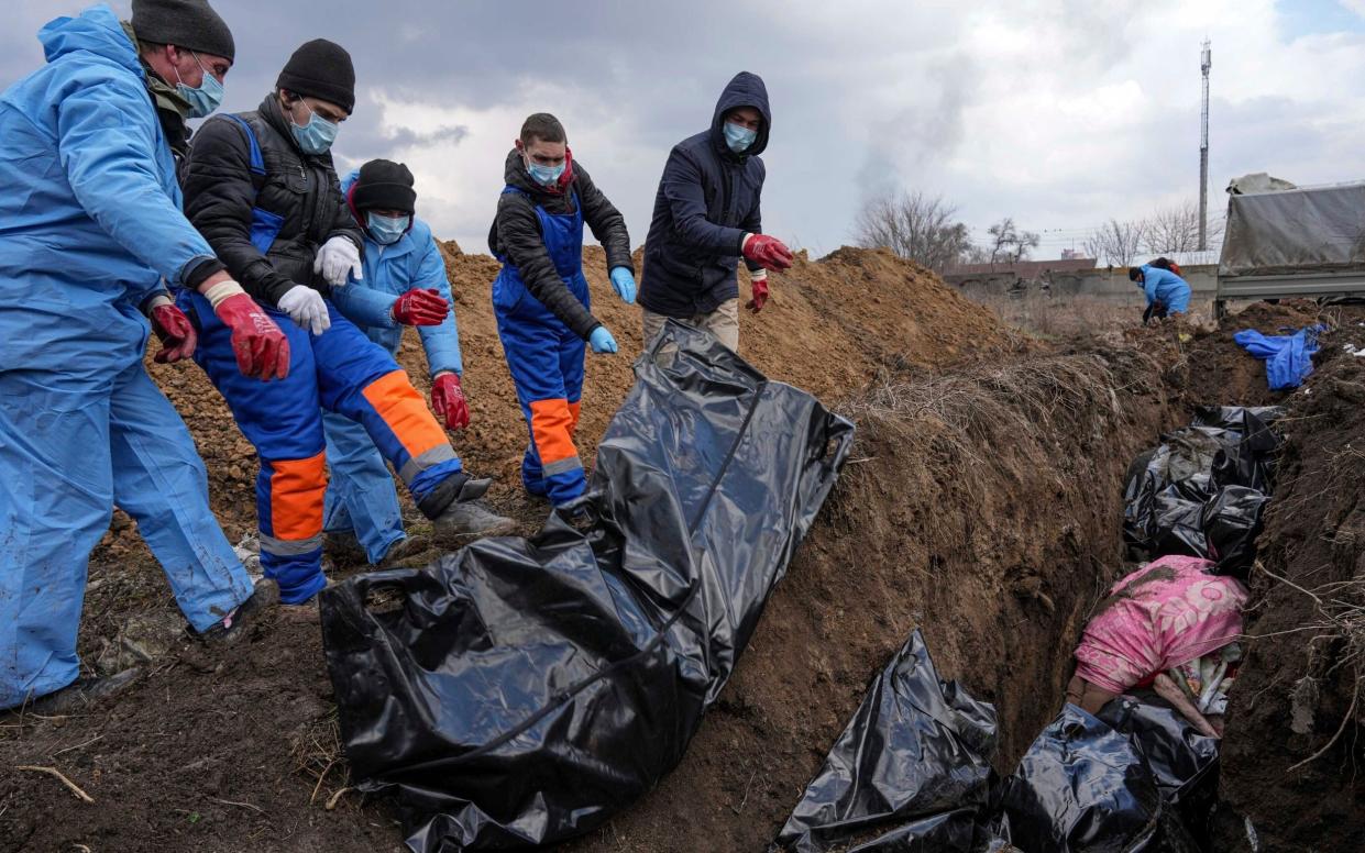 Dead bodies are placed into a mass grave on the outskirts of Mariupol - Evgeniy Maloletka/AP