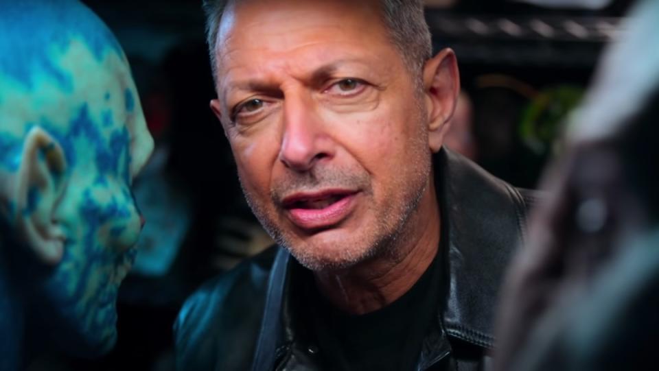 Jeff Goldblum stands close to a prop monster in a commercial for the actor's National Geographic show, The World According to Jeff Goldblum.