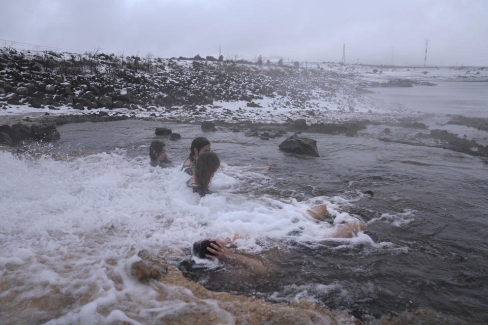 Israelis bathe in a hot water coming out of a pipe from a drilling project which exposed a subterranean hydrothermal spring, at a snow-covered reservoir next to Mount Bental in the Israeli-controlled Golan Heights, near the Israeli border with Syria Wednesday, Jan. 19, 2022. Snow fell in the Middle East as a winter storm swept through the region. (AP Photo/Ariel Schalit)