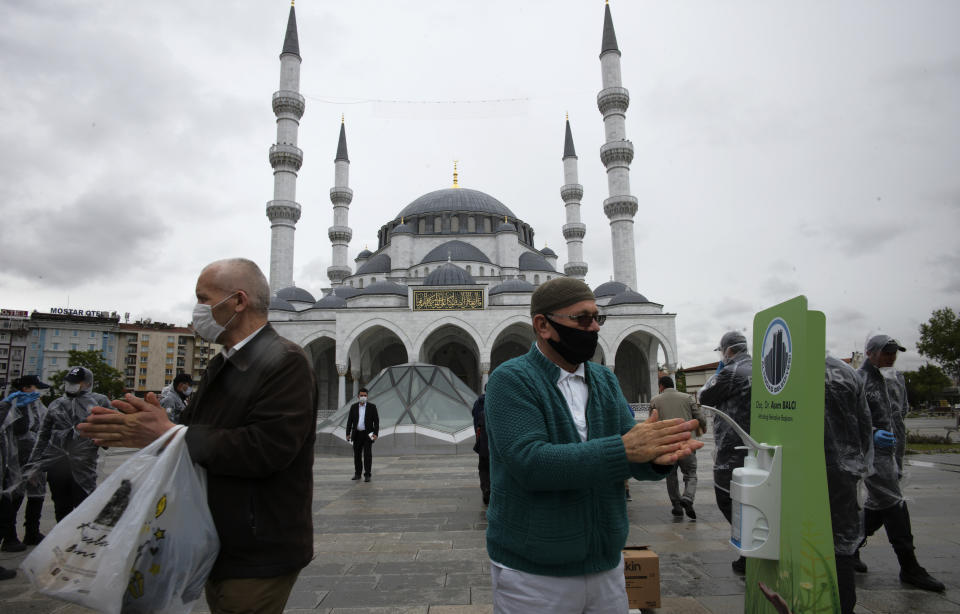 People, wearing face masks to protect against coronavirus, disinfect their hands as they arrive to attend Friday prayers, outside Melike Hatun Mosque, in Ankara, Turkey, Friday, May 29, 2020. Worshippers in Turkey have held their first communal Friday prayers in 74 days after the government re-opened some mosques as part of its plans to relax measures in place to fight the coronavirus outbreak. Prayers were held in the courtyards of a select number of mosques on Friday, to minimize the risk of infection. (AP Photo/Burhan Ozbilici)