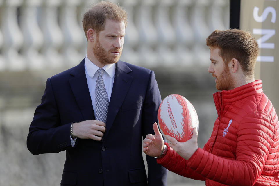 Britain's Prince Harry listens to Rugby League World Cup 2021 (RLWC2021) ambassador James Simpson in the gardens at Buckingham Palace in London, Thursday, Jan. 16, 2020. Prince Harry, the Duke of Sussex will host the Rugby League World Cup 2021 draw at Buckingham Palace, prior to the draw, The Duke met with representatives from all 21 nations taking part in the tournament, as well as watching children from a local school play rugby league in the Buckingham Palace gardens. (AP Photo/Kirsty Wigglesworth)