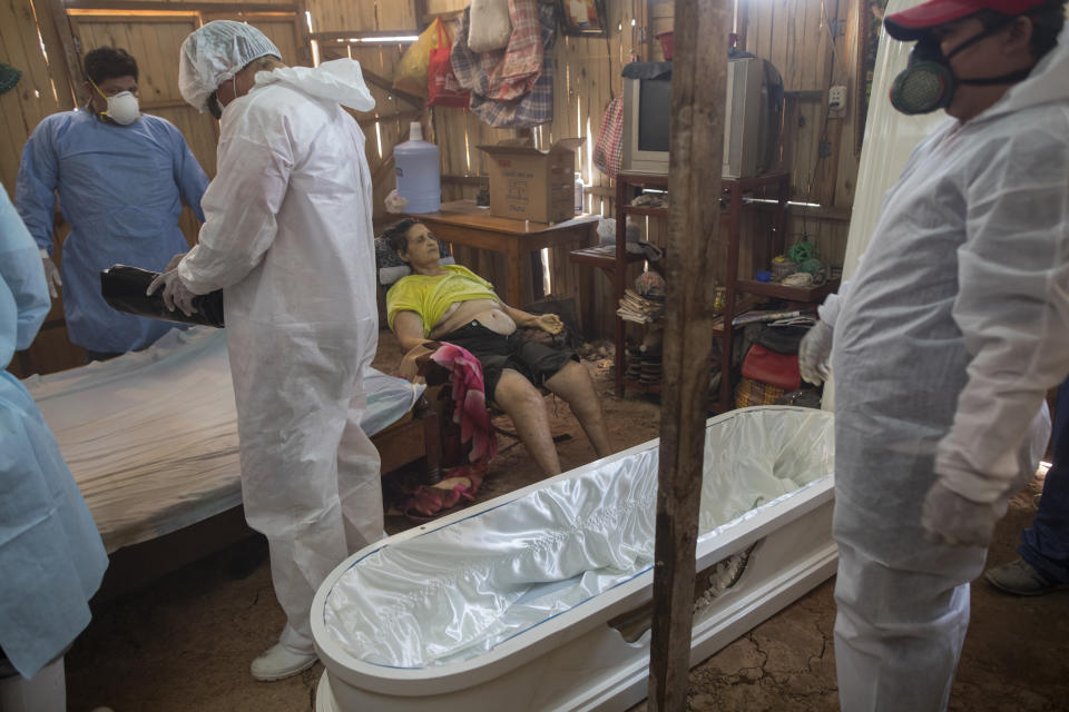 A government team prepares to remove the body of Susana Cifuentes who died in her home from symptoms related to the new coronavirus at the age of 71, in the Shipibo Indigenous community of Pucallpa, in Peru’s Ucayali region, Tuesday, Sept. 1, 2020. While the lucky are cured with ancestral ailments, the less fortunate often die at home. A government team travels from one spartan, thatch-roofed home to the next, removing the dead from their homes where they took their last breaths. (AP Photo/Rodrigo Abd)
