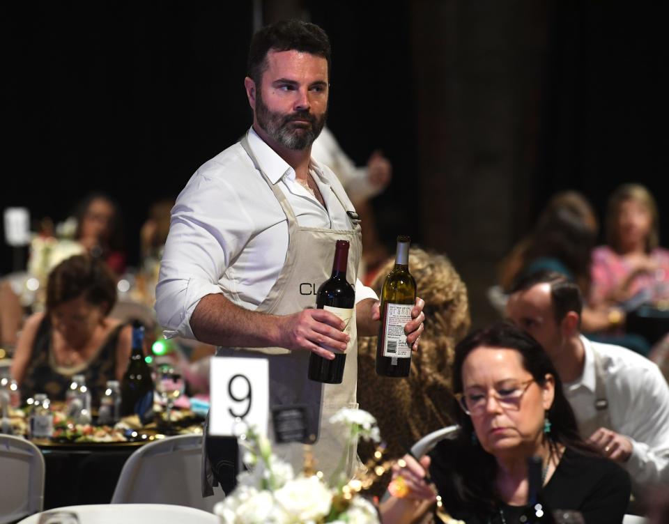 Abilene City Council member Blaise Regan walks through the crowd at Wine, Women & Shoes, carrying two bottles ready to pour for any of the guests during Thursday’s benefit.