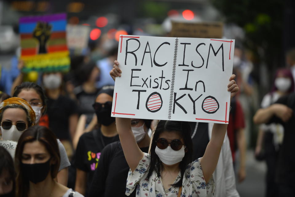 A demonstrator holds up a sign that reads "Racism exists in Tokyo" at a Saturday protest in Tokyo. (Photo: Anadolu Agency via Getty Images)