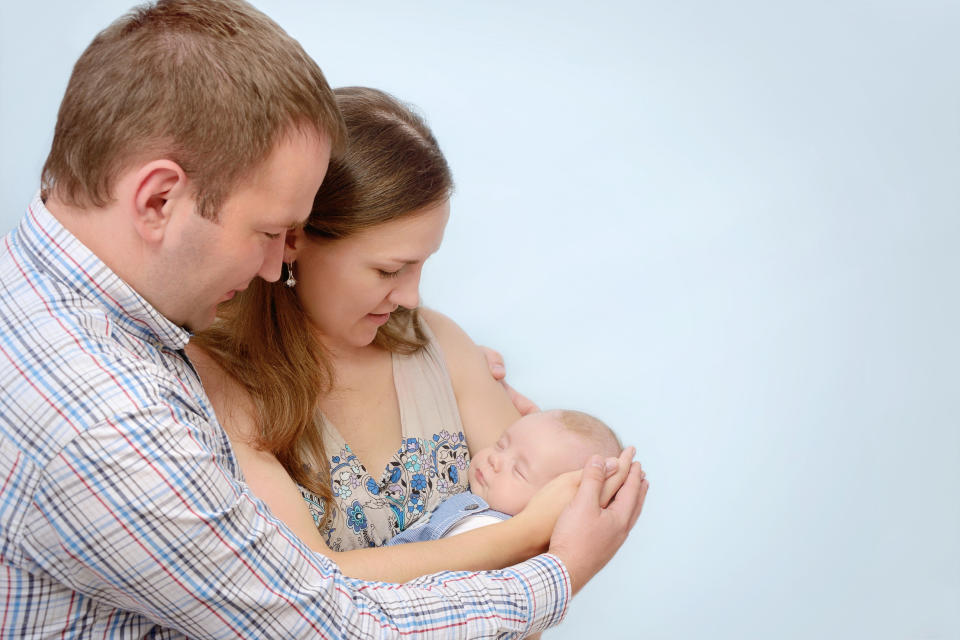 A married couple cradling their newborn baby.
