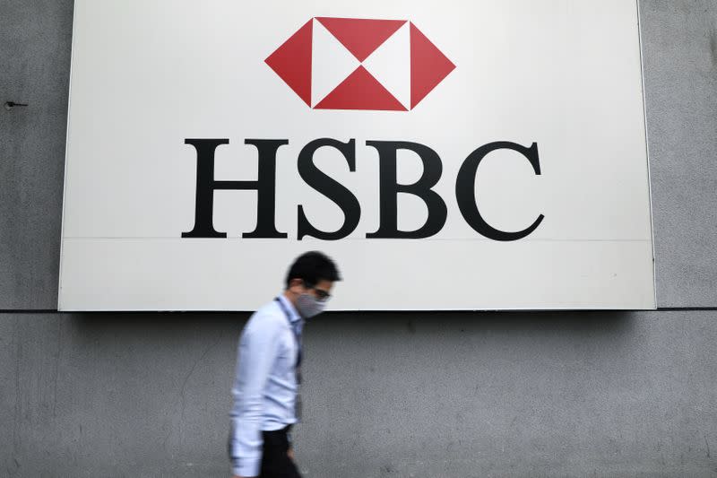 A man wearing a protective mask walks past a logo of HSBC at its headquarters, amid the coronavirus disease (COVID-19) outbreak in Kuala Lumpur