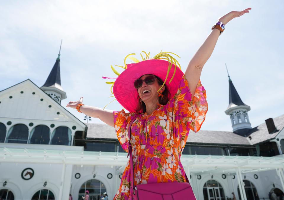 Becky Gaslin of Louisville holds up her arms as she poses on the second level of the Paddock as friend Venus Marcum takes her picture Thursday May 2, 2024 at Churchill Downs in Louisville, Ky.