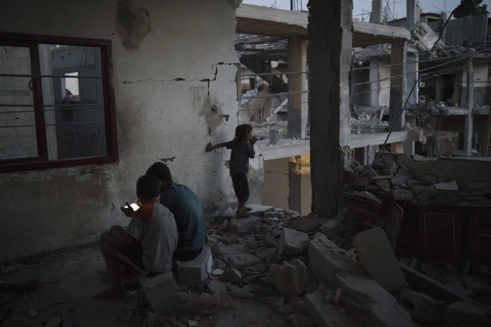 Chadi Nassir, 7, looks out of a room as two of his brothers play video games in their home, heavily damaged by airstrikes in Beit Hanoun, northern Gaza Strip, Friday, June 11, 2021. (AP Photo/Felipe Dana)