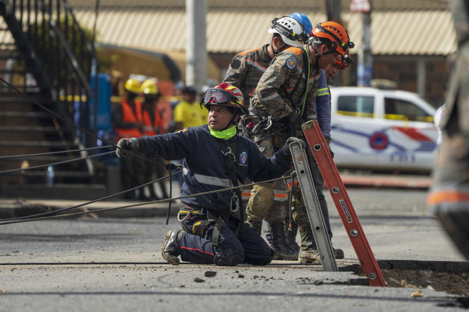 Rescue workers prepare to descend into a sinkhole in Villa Nueva, Guatemala, Sunday, Sept. 25, 2022. Rescuers are searching for people who are believed to have fallen into the sinkhole while driving their vehicle, while four others were rescued alive from the scene on Saturday night. (AP Photo/Moises Castillo)