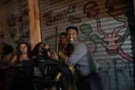 People listen to a street performance by the Brazilian band Atitude Nossa as the restrictions related to the COVID-19 pandemic are eased in Rio de Janeiro, Brazil, Monday, Oct. 5, 2020. Since the beginning of October, live shows are now permitted in Rio de Janeiro. (AP Photo/Silvia Izquierdo)