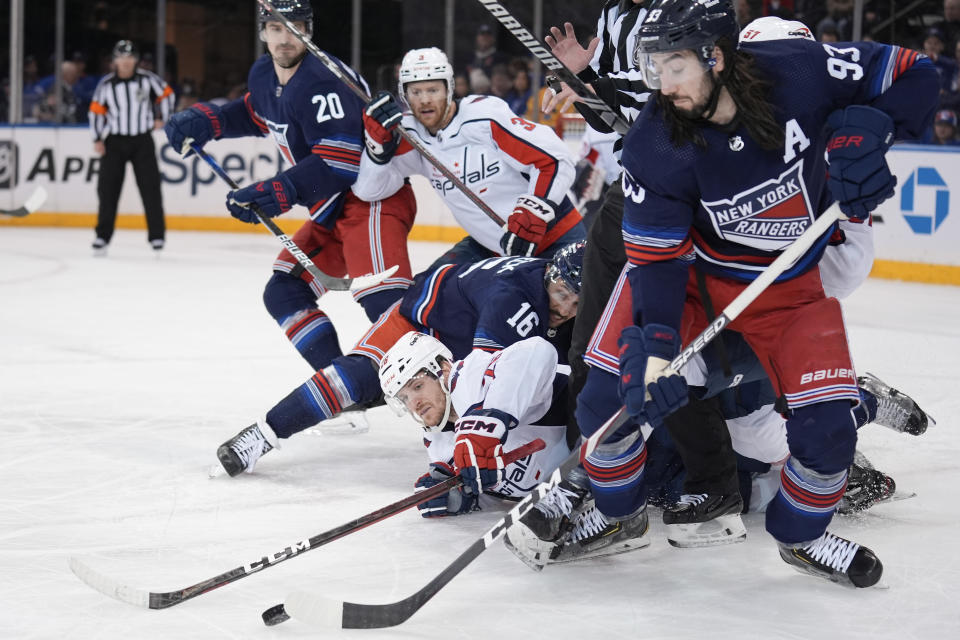 Washington Capitals' Nic Dowd, bottom, reaches for the puck after a face off during the third period of an NHL hockey game against the New York Rangers, Sunday, Jan. 14, 2024, in New York. (AP Photo/Seth Wenig)