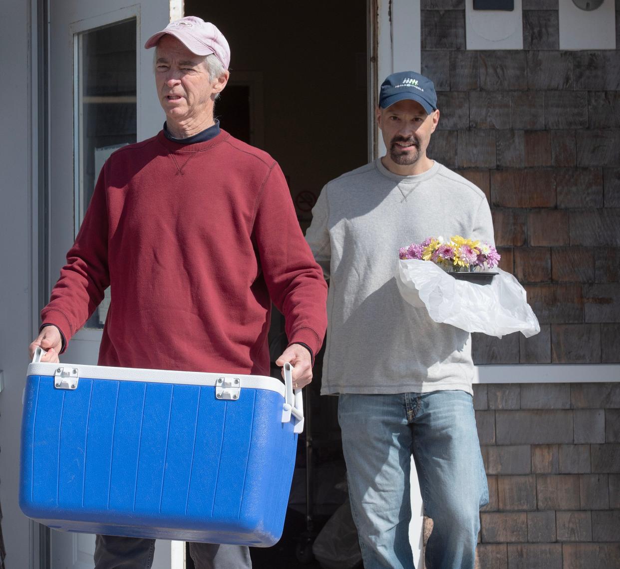 Meals on Wheels driver Richard DeSorgher heads out of the Mashpee Senior Center Thursday with a cooler full of meals, followed by Lou Eppers with flowers for each customer for May Day. DeSorgher has been driving for six years, dropping off 26 meals on his two-hour route.