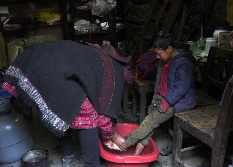 A woman washes her son's feet before sending him off to school in Tupe, Peru, Tuesday, July 19, 2022. As Peru´s President Pedro Castillo marks the first anniversary of his presidency, his popularity has been decimated by his chaotic management style and corruption allegations, but in rural areas like Tupe, voters believe the fault for the executive crisis lies not only with Castillo, but with Congress, which has sought to remove him twice.(AP Photo/Martin Mejia)