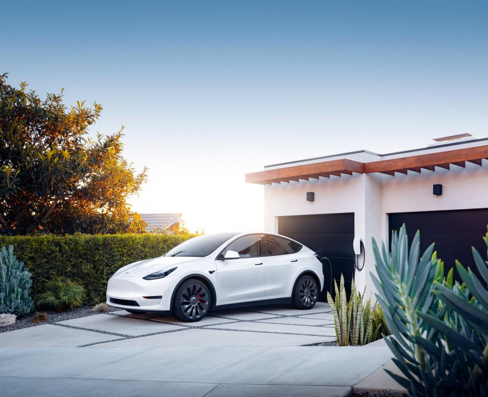 The Tesla Model Y electric SUV charging at a home.