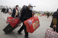 In this Thursday, April 2, 2020, photo, a man crosses the expressway gate at the border into Wuhan city in central China's Hubei province. Millions of Chinese workers are streaming back to factories, shops and offices but many still face anti-coronavirus controls that add to their financial losses and aggravation. In Wuhan police require a health check and documents from employers for returning workers. (AP Photo/Ng Han Guan)