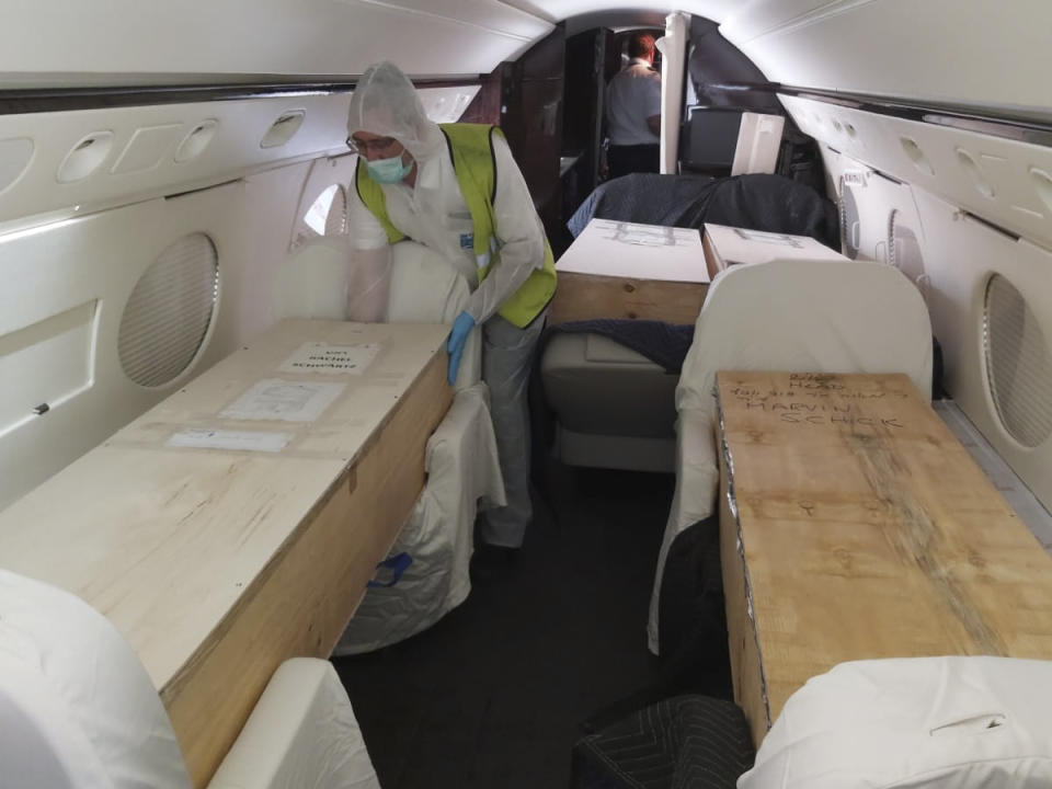 In this Monday, April 27, 2020 photo released by ZAKA, a voluntary emergency team, a team member unloads a coffin from a plane at Ben Gurion airport in Israel. Air travel to Israel has come to a near standstill due to coronavirus restrictions, but one type of voyage still endures: the final journey of Jews wishing to be buried in Israel. Families, the aviation industry and health workers are finding ways to keep the deceased flying in despite the challenges presented by the virus. (Michael Gutwein, ZAKA via AP)