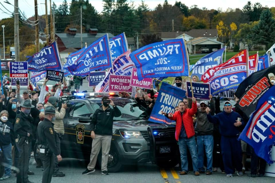 Supporters of President Donald Trump line the road as the motorcade for Democratic presidential nominee Joe Biden makes its way to a drive-in campaign rally at Dallas High School on October 24, 2020 in Dallas, Pennsylvania. (Photo by Drew Angerer/Getty Images)