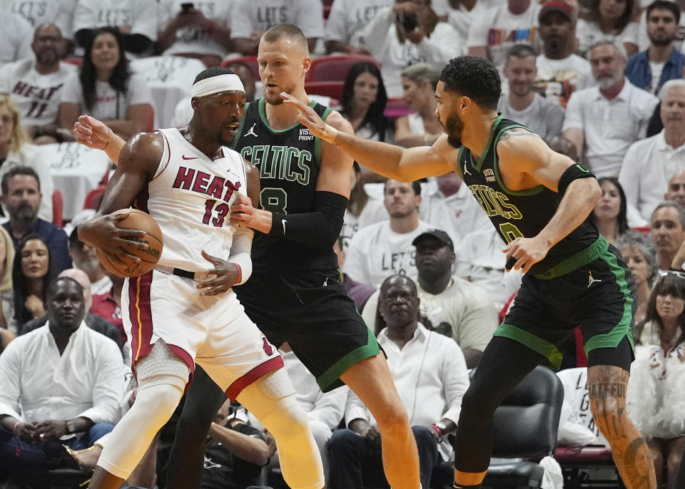 Boston Celtics center Kristaps Porzingis (8) and forward Jayson Tatum (0) defend against Miami Heat center Bam Adebayo (13) during the first half of Game 4 of an NBA basketball first-round game, Monday, April 29, 2024, in Miami. (AP Photo/Marta Lavandier)