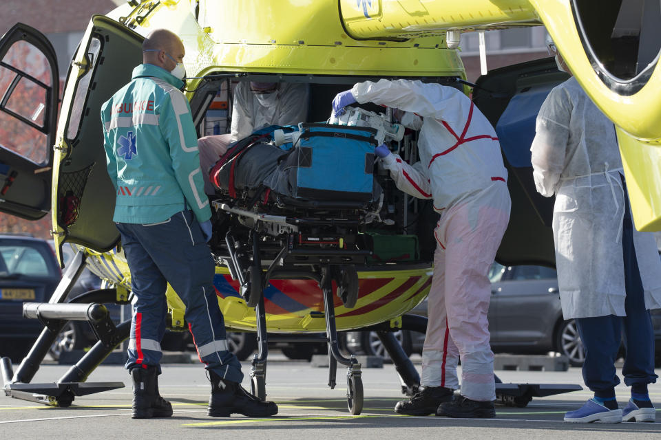 A COVID-19 patient is being carried into a helicopter at Flevoziekenhuis, or FlevoHospital, in Almere, Netherlands, Friday, Oct. 23, 2020. In the latest sign of the scale of the coronavirus pandemic sweeping across Europe, a helicopter is scheduled to start airlifting COVID-19 patients from the Netherlands to an intensive care unit in the German city of Muenster.(AP Photo/Peter Dejong)