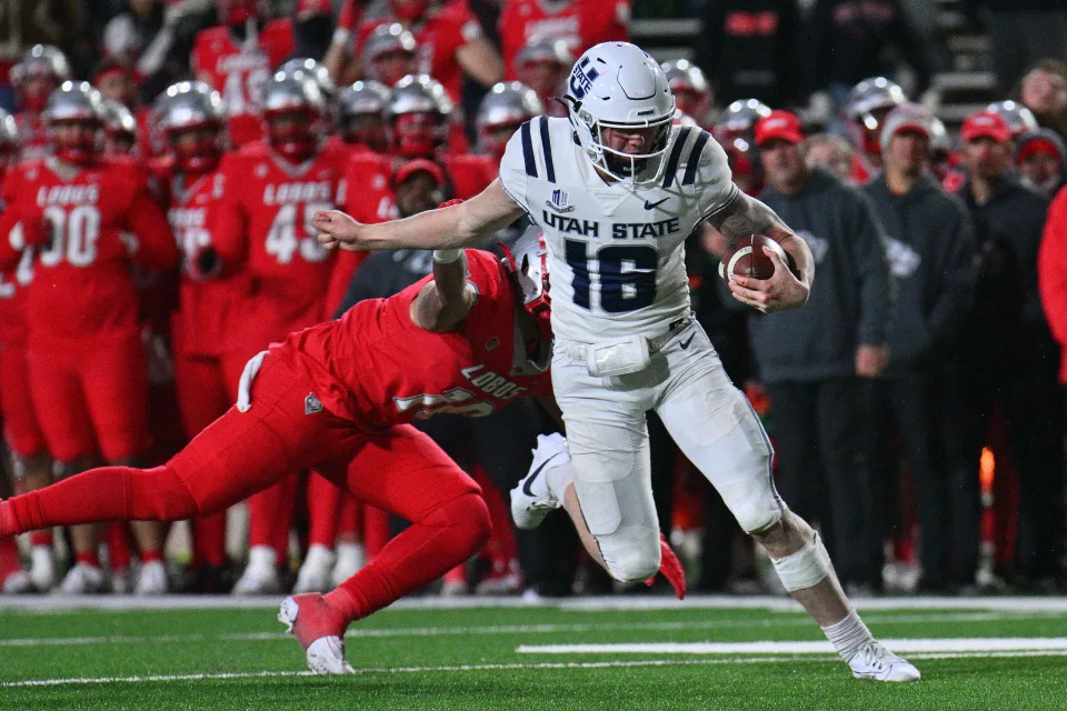 ALBUQUERQUE, NEW MEXICO - NOVEMBER 24: Quarterback Levi Williams #16 of the Utah State Aggies scrambles past linebacker Dimitri Johnson #16 of the New Mexico Lobos for the game-winning touchdown against the New Mexico Lobos during the second overtime of their game at University Stadium on November 24, 2023 in Albuquerque, New Mexico. The Aggies defeated the Lobos 44-41 in 2OT. (Photo by Sam Wasson/Getty Images)