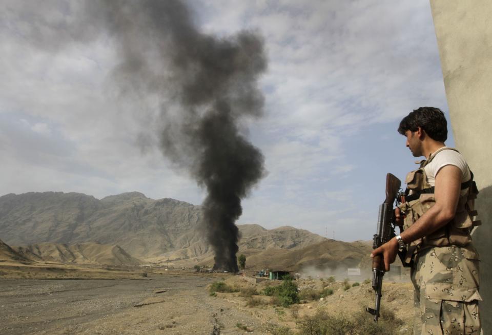 Afghan security forces keep watch as smoke rises from burning NATO supply trucks after, what police officials say, was an attack by militants in the Torkham area near the Pakistani-Afghan in Nangarhar Province June 19, 2014. (REUTERS/Parwiz)