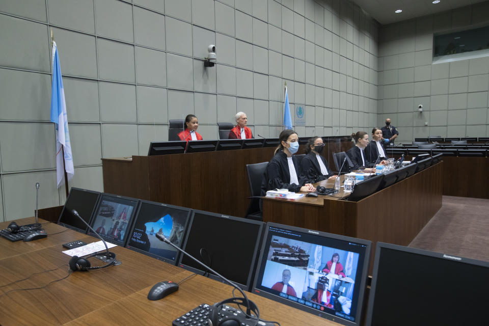 Presiding judge David Re, second left, and judge Janet Nosworthy, left, and the prosecution and defense counsel seen on screens via video link due to COVID-19 measures, open the session of the United Nations-backed Lebanon Tribunal where it is scheduled to hand down it's sentencing on Salim Jamil Ayyash, a member of the Hezbollah militant group who was convicted of involvement in the assassination of former Lebanese Prime Minister Rafik Hariri and 21 others 15 years ago, in Leidschendam, Netherlands, Friday Dec. 11, 2020. Ayyash is not in custody and is unlikely to serve any sentence. (AP Photo/Peter Dejong, Pool)