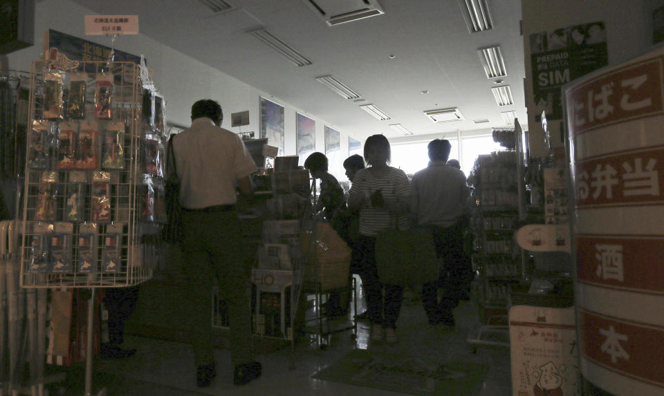 People shop at a store during a blackout at Hakodate airport in Hakodate, Hokkaido, northern Japan following a strong earthquake Thursday, Sept. 6, 2018. A powerful earthquake rocked Japan's northernmost main island of Hokkaido early Thursday, triggering landslides that crushed homes, knocking out power and forcing a nuclear power plant to switch to a backup generator. (Kyodo News via AP)