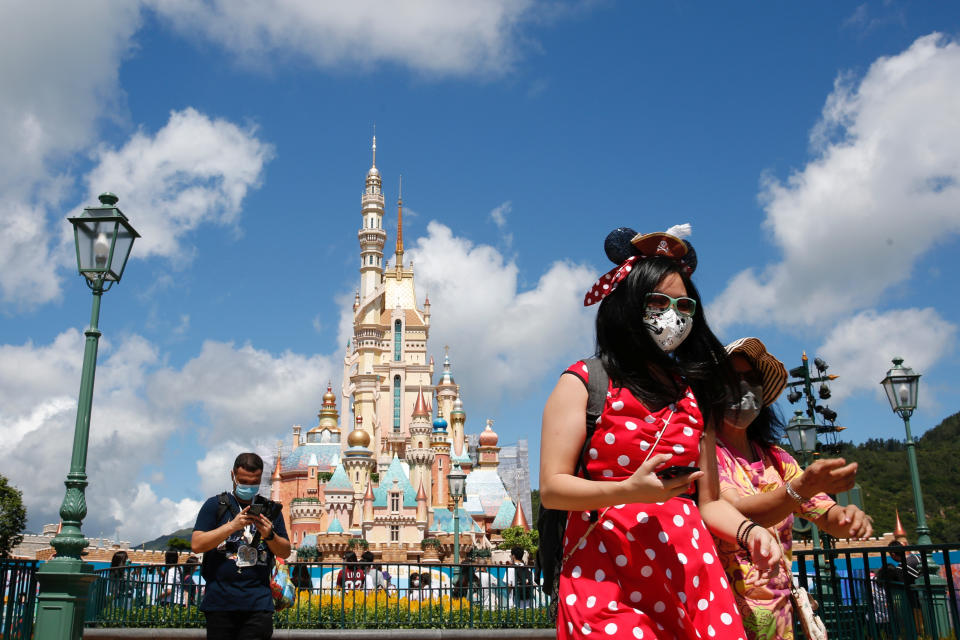 Visitors wearing protective face masks walk at the Disneyland theme park after it reopened following a shutdown due to the coronavirus disease (COVID-19) in Hong Kong, China June 18, 2020. REUTERS/Tyrone Siu