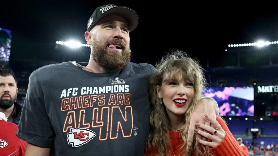 Travis Kelce wearing a "champions" t-shirt with his arm around Taylor Swift after winning the AFC Championship