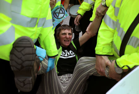 Police officers detain a climate change activist at Oxford Circus during the Extinction Rebellion protest in London, Britain April 18, 2019. REUTERS/Simon Dawson