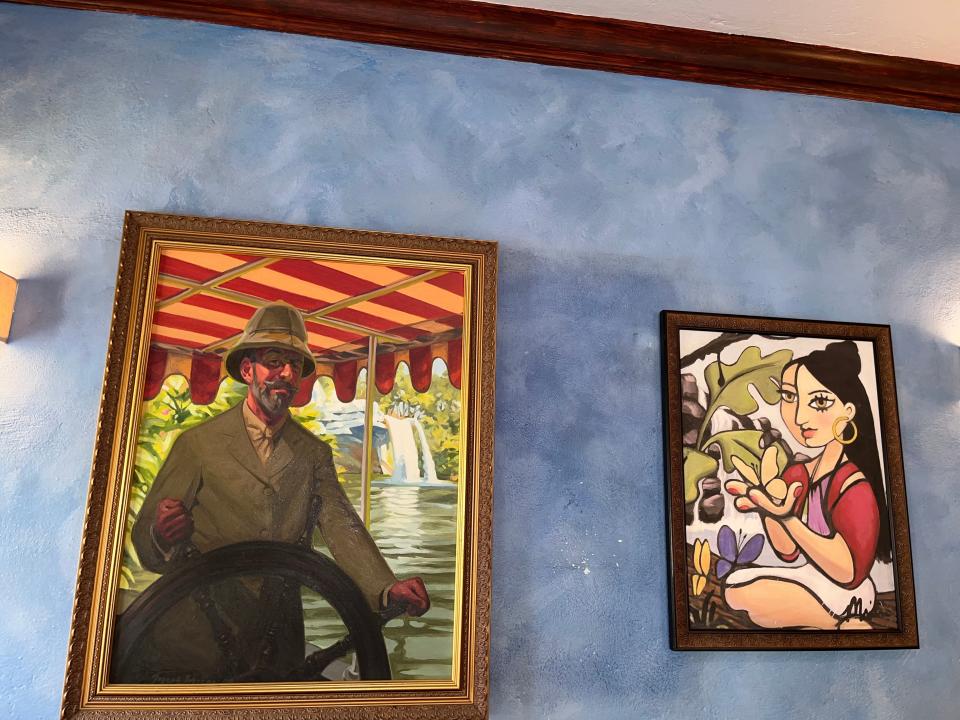 paintings hanging in the indoor waiting area at skipper canteen in magic kingdom