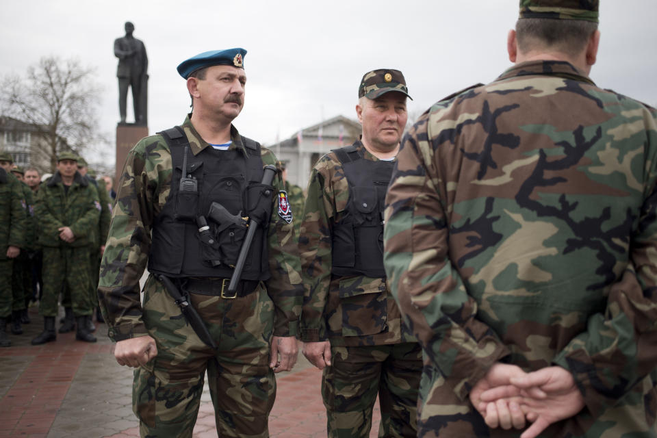 Members of the Crimean self defense forces gather for their morning briefing prior to a patrol duty near Soviet Union founder Vladimir Lenin's statue in the background in Simferopol, Crimea, early Thursday, March 27, 2014. Crimea’s government has decided to disband self-defense forces which provided help to the Russian military which have been occupying since late February. (AP Photo/Pavel Golovkin)