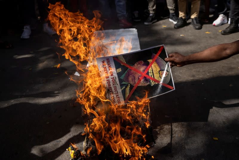 A Myanmar citizen living in India burns a poster of Myanmar's army chief Senior General Min Aung Hlaing with his face crossed out during a protest against the military coup in Myanmar, in New Delhi