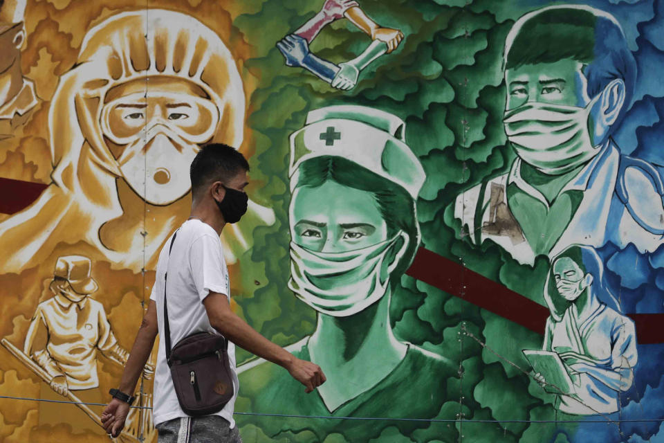 A man wearing a protective mask to prevent the spread of the coronavirus walks beside a mural of health workers outside the Mission Hospital in Pasig, Philippines, Monday, Feb. 22, 2021. Delays have hounded the delivery of COVID-19 to the Philippines, with officials saying the scheduled arrival on Tuesday of 600,000 doses of donated vaccine from Sinovac Biotech Ltd. may be delayed because the China-based firm still lacks an authorization from Manila's Food and Drug Administration for the emergency use of it's vaccine. (AP Photo/Aaron Favila)