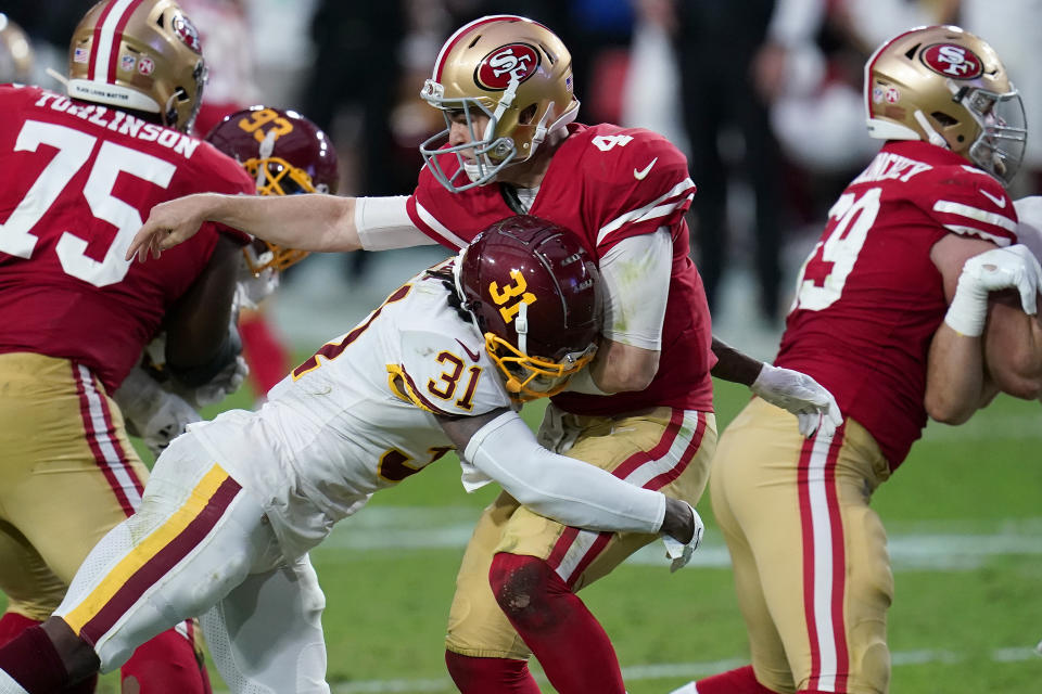 San Francisco 49ers quarterback Nick Mullens (4) takes a hit after the throw by Washington Football Team strong safety Kamren Curl (31) during the first half of an NFL football game, Sunday, Dec. 13, 2020, in Glendale, Ariz. (AP Photo/Ross D. Franklin)