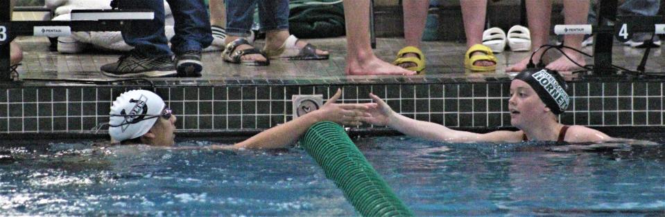 Lily Knudsen of Pueblo County shakes hands with Nicole Abraham of Pueblo South after the 400-yard freestyle relay at the South-Central League finals held at Pueblo County High School on Feb. 4, 2023.