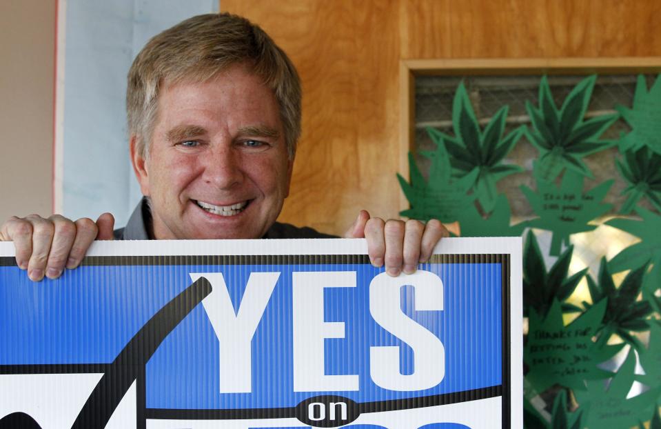 In this Monday, Nov. 26, 2012 photo, travel guide author and marijuana legalization supporter Rick Steves holds a campaign sign in his office in Edmonds, Wash next to a door covered with marijuana leaf-shaped notes from his staff congratulating him on the passage of a referendum legalizing marijuana in the state. In the late-1980s heyday of the "Just Say No" campaign, a man calling himself “Jerry” appeared on a Seattle radio station’s midday talk show, using a pseudonym because he was a businessman, afraid of what his customers would think if they heard him criticizing U.S. marijuana laws. A quarter century later, "Jerry" had no problem using his real name - Rick Steves - as one of the main forces behind Washington’s successful ballot measure to legalize, regulate and tax marijuana for adults over 21. (AP Photo/Elaine Thompson)