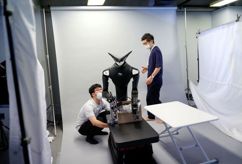 Staff members of Telexistence check the copmany's shelf-stacking avatar robot, designed to resemble a kangaroo and developed to work in a convenience store, during a photo opportunity ahead of its unveiling in Tokyo, Japan
