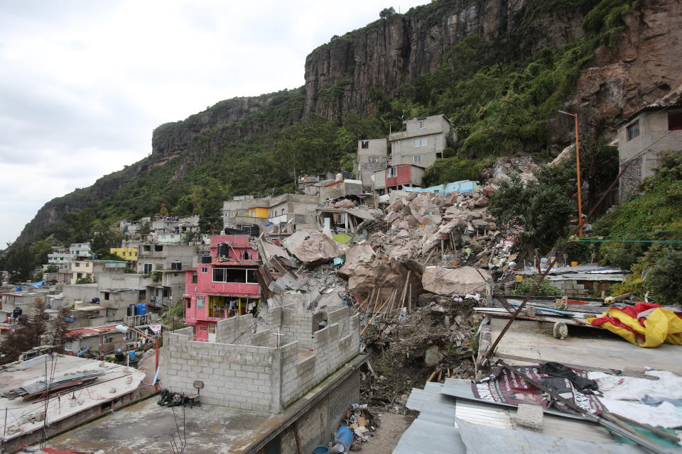 Boulders and debris that plunged from a mountainside rest atop homes in Tlalnepantla, on the outskirts of Mexico City, Saturday, Sept. 11, 2021. A section of a mountain on the outskirts of Mexico City gave way Friday, plunging rocks the size of small homes onto a densely populated neighborhood and leaving at least one person dead and 10 others missing. (AP Photo/Ginnette Riquelme)